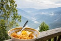 Noodles and omelette served in a bowl for breakfast. Photo taken with background of hills and river valley