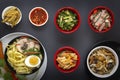 Noodles with pieces of meat and egg in a black plate and dim sum with different traditional snacks of mushrooms, soy Royalty Free Stock Photo