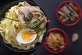 Noodles with pieces of meat and egg in a black plate and dim sum with different traditional snacks of mushrooms, soy Royalty Free Stock Photo