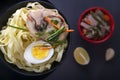 Noodles with pieces of meat and egg in a black plate and dim sum with different traditional snacks of mushrooms Royalty Free Stock Photo