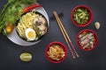 Noodles with pieces of meat and egg in a black plate and dim sums with different traditional snacks of mushrooms, soy Royalty Free Stock Photo