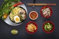 Noodles with pieces of meat and egg in a black plate and dim sums with different traditional snacks of mushrooms, soy Royalty Free Stock Photo