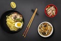 Noodles with pieces of meat and egg in a black plate and dim sums with different traditional snacks of mushrooms, soy Royalty Free Stock Photo