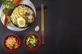 Noodles with pieces of meat and egg in a black plate and dim sums with different traditional snacks of mushrooms Royalty Free Stock Photo