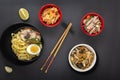 Noodles with pieces of meat and egg in a black plate and dim sums with different traditional snacks of mushrooms Royalty Free Stock Photo