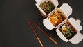 Noodles with pork and vegetables in take-out box on black table Royalty Free Stock Photo