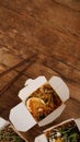 Noodles with pork and vegetables in take-out box on wooden table Royalty Free Stock Photo