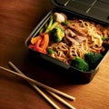 Noodles with pork and vegetables in take-out box on wooden table Royalty Free Stock Photo