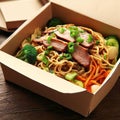 Noodles with pork and vegetables in take-out box on wooden table Royalty Free Stock Photo