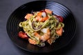 Noodles with seafood, sun-dried tomatoes, capers and red onions. Homemade pasta with shrimp, salmon trout and pesto sauce. Royalty Free Stock Photo