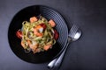 Noodles with seafood, sun-dried tomatoes, capers and red onions. Homemade pasta with shrimp, salmon trout and pesto sauce. Black Royalty Free Stock Photo