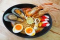 Noodles spicy shrimp soup in black bowl on wooden table