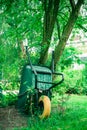 Wheelbarrow stands against a tree, Communal city garden