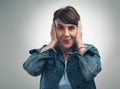 Nope, dont wanna hear it. Studio portrait of a senior woman covering her ears against a grey background.