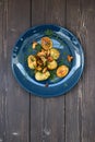 Nordic cuisine. Healthy vegetarian meal. Fried forest mushrooms, potatoes and dill on navy blue plate on rustic dark background c