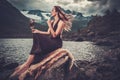 Nordic goddess in ritual garment with hawk near wild mountain lake in Innerdalen valley.