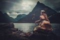Nordic goddess in ritual garment with hawk near wild mountain lake in Innerdalen valley. Royalty Free Stock Photo