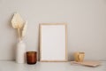 Nordic style home office desk in living room. Picture frame mockup, candle, dry flowers in vase, cup of tea, paper notebook on Royalty Free Stock Photo