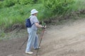 Nordic Walking-elderly woman in a striped blouse going uphill