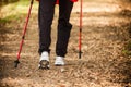 Nordic walking. Female legs hiking in forest or park. Royalty Free Stock Photo