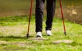 Nordic walking. Female legs hiking in the park. Royalty Free Stock Photo