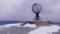 Famous metal globe sculpture located on the top of a cliff at North Cape over the arctic sea without people in winter.