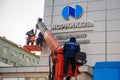 Norilsk, Russia - March 5, 2020: the operator controls the crane, workers hang a sign on the building.