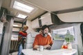 Daily normal life inside a camper van rv mobile home. Woman cooking in the kitchen and adult man working on laptop computer. Royalty Free Stock Photo