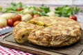 Normal view of a typical Spanish potato omelette with a separate portion with potatoes and cherrie tomatoes in a rustic setting. Royalty Free Stock Photo