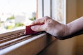 Normal view of a woman`s hands with a sandpaper sanding a window frame before painting. Empowered woman concept Royalty Free Stock Photo