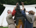 Norman soldiers dressing a soldiers with chain mail at the reenactment of The Battle of Hastings in the UK