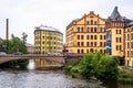 Old yellow industrial building with bridge over river with incidental people in Norrkoping Sweden.