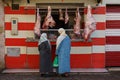 Morocco. Taroudant. Two women in traditional dress in front of a storefront of a butcher\'s shop