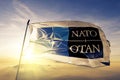 North Atlantic Treaty Organization NATO OTAN logo. flag textile cloth fabric waving on the top sunrise mist fog