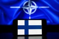 The North Atlantic Treaty Organization on screens. Finland flag on screen and NATO flag in background