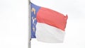 North Carolina State flag waves in slow motion against white sky