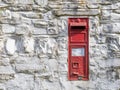 NORTH DEVON, MARCH 13 2022: Bright red Victorian Post Office post box in old wall. Devon, UK. Royalty Free Stock Photo