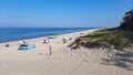 North German white sandy beach on the North Sea. A few tourists sunbathe. Blue calm sea against a blue sky and grassy dunes. North Royalty Free Stock Photo