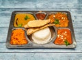 north indian vegetarian meal thali with curry, rice, chapati and vegetables served in dish isolated on wooden table top view of Royalty Free Stock Photo