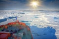 Icebreaker makes its way to North pole through pack ice. On bow of ship tourists, ice box with opennings