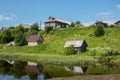 North Russian village Isady. Summer day, Emca river, old cottages on the shore, old wooden bridge and clouds reflections. Royalty Free Stock Photo