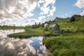 North Russian village Isady. Summer day, Emca river, old cottages on the shore, old wooden bridge and clouds reflections. Royalty Free Stock Photo