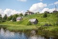 North Russian village Isady. Summer day, Emca river, old cottages on the shore, old wooden bridge and clouds reflections. Royalty Free Stock Photo