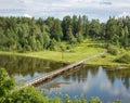 North Russian village Isady. Summer day, Emca river, old cottages on the shore, old wooden bridge and clouds reflections. Royalty Free Stock Photo