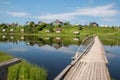 North Russian village Isady. Summer day, Emca river, old cottages on the shore, old wooden bridge and clouds reflections. Royalty Free Stock Photo