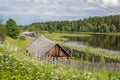 North Russian village Isady. Summer day, Emca river, old cottages on the shore, old wooden bridge and clouds reflections.