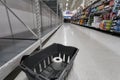 NORTH VANCOUVER, BC, CANADA - MAR 19, 2020: An empty shelf with a single roll of toilet paper in a shopping basket at a