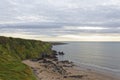 The Northern extremity of the sandy beach at the St Cyrus Nature Reserve with its eroded cliffs and rocks in the North Sea.