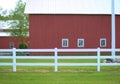 Red farm buildings and a white fence surrounded by green lawn Royalty Free Stock Photo