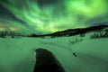 Northern lights above a water stream in a winter landscape. Royalty Free Stock Photo